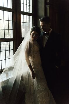 a bride and groom standing in front of a window