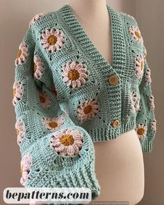 a crocheted shawl with flowers on the front and back, sitting on top of a mannequin