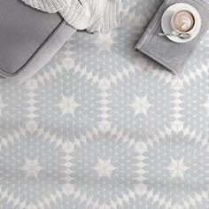 an overhead view of a coffee cup, book and blanket on a bed with pillows