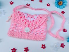 a pink crocheted purse sitting on top of a table next to blue flowers