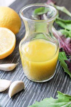 a glass bottle filled with orange juice next to some vegetables and garlic on a table