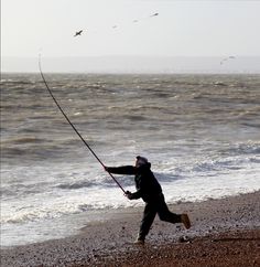 a man is fishing on the beach by the water