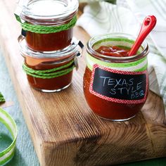 three jars filled with sauce sitting on top of a wooden cutting board