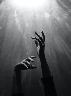 two hands reaching up into the air above water