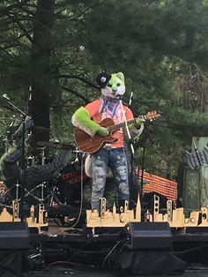 a man with a guitar on stage in front of some microphones and other musical instruments