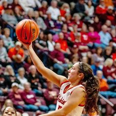 a female basketball player about to dunk the ball in front of an arena full of people