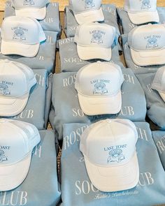 many hats are laid out in rows on top of each other, with the same blue and white logo