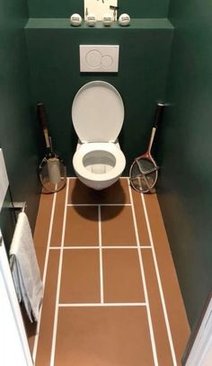 there is a toilet in the bathroom with green walls and brown tile on the floor