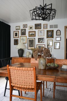 a dining room table with chairs and pictures on the wall