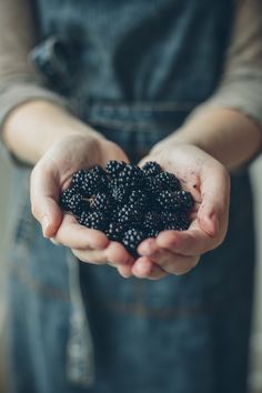 a person holding some blackberries in their hands