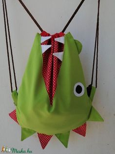 a green bag with red and white polka dots hanging from it's side on a wall