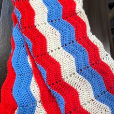 an american flag crocheted afghan is displayed on a bench with the colors red, white and blue