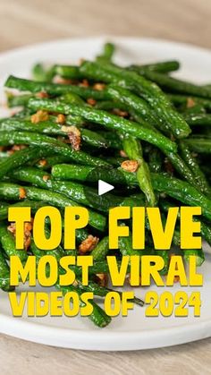 a white plate topped with green beans on top of a wooden table and the words top five most viral videos of 2014