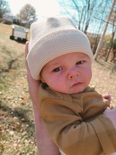 a baby is wearing a hat while being held by someone