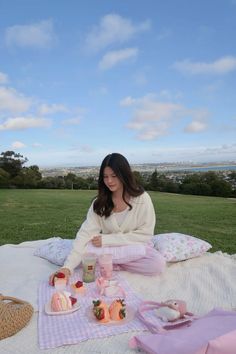 a woman sitting on top of a blanket eating food