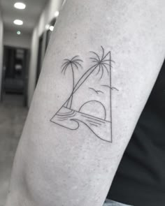 a man's arm with a small tattoo of a sailboat and palm trees