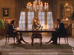 two people sitting at a table in front of a chandelier