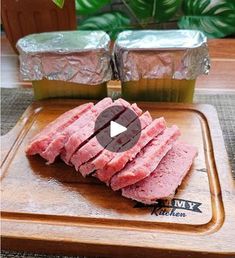 sliced meat on a cutting board next to two containers of sauce and a potted plant