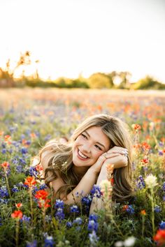 a mother and her daughter laying in a field of wildflowers smiling at the camera