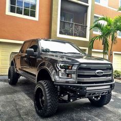 a black truck parked in front of a building with palm trees on the side of it