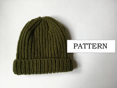 a green knitted hat sitting on top of a white table next to the word pattern