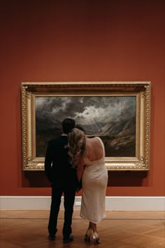 a man and woman standing in front of a painting