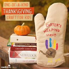 an oven mitt sitting on top of a wooden table next to books and a pumpkin