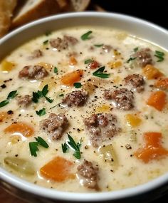 a bowl of soup with meatballs and carrots next to a piece of bread