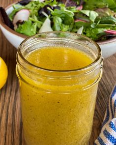 a jar filled with yellow liquid next to a salad