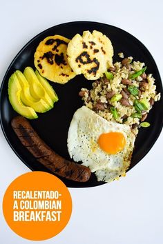 a black plate topped with eggs, rice and sausage