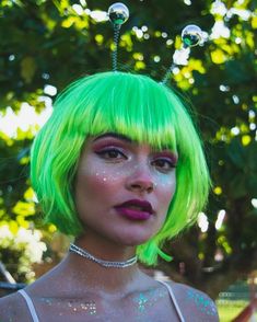 a woman with bright green hair and glitter on her face is posing for the camera