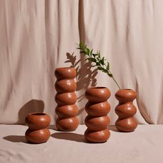 three brown vases sitting next to each other with a plant growing out of them