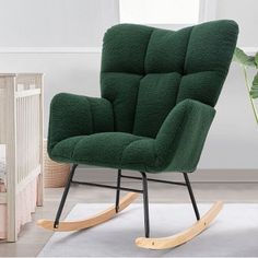 a green rocking chair next to a baby crib with a plant in the corner