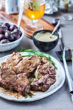 a plate with some meat on it next to bowls of food and utensils