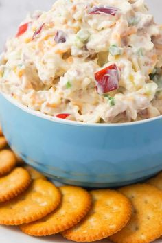 a blue bowl filled with chicken salad surrounded by crackers