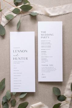 two white wedding programs with greenery on top