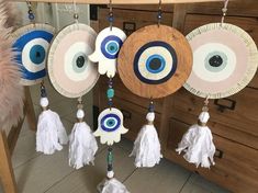 an eyeball and tassels hanging from a wooden frame on a table with drawers in the background