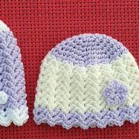 two crocheted hats sitting next to each other on a red cloth covered table