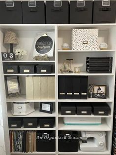 a white bookcase filled with lots of black and white boxes on top of it