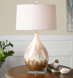 a lamp sitting on top of a wooden table next to a potted green plant