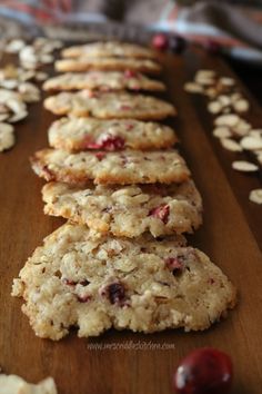 cookies with cranberries and almonds are lined up on a cutting board, ready to be eaten