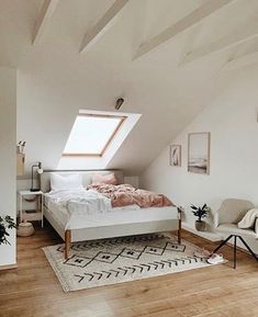 an attic bedroom with white walls and wooden floors