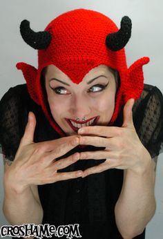 a woman wearing a red hat with horns on her head and hands in front of her face