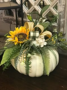 a white pumpkin decorated with sunflowers and greenery