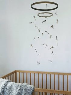 a crib with a blanket on top of it next to a wall hanging from the ceiling