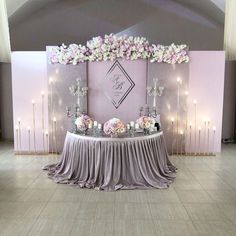 a table with flowers and candles on it in front of a wall that has lights