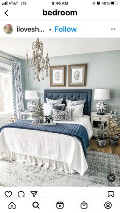 a blue and white bedroom with chandelier above the bed