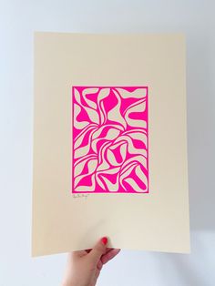 a person holding up a pink and white paper with an abstract design in the middle