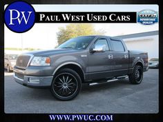 a gray truck parked in a parking lot next to a building with the words paul west used cars on it