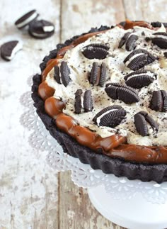 an oreo cookie pie on top of a white cake plate with cookies and cream